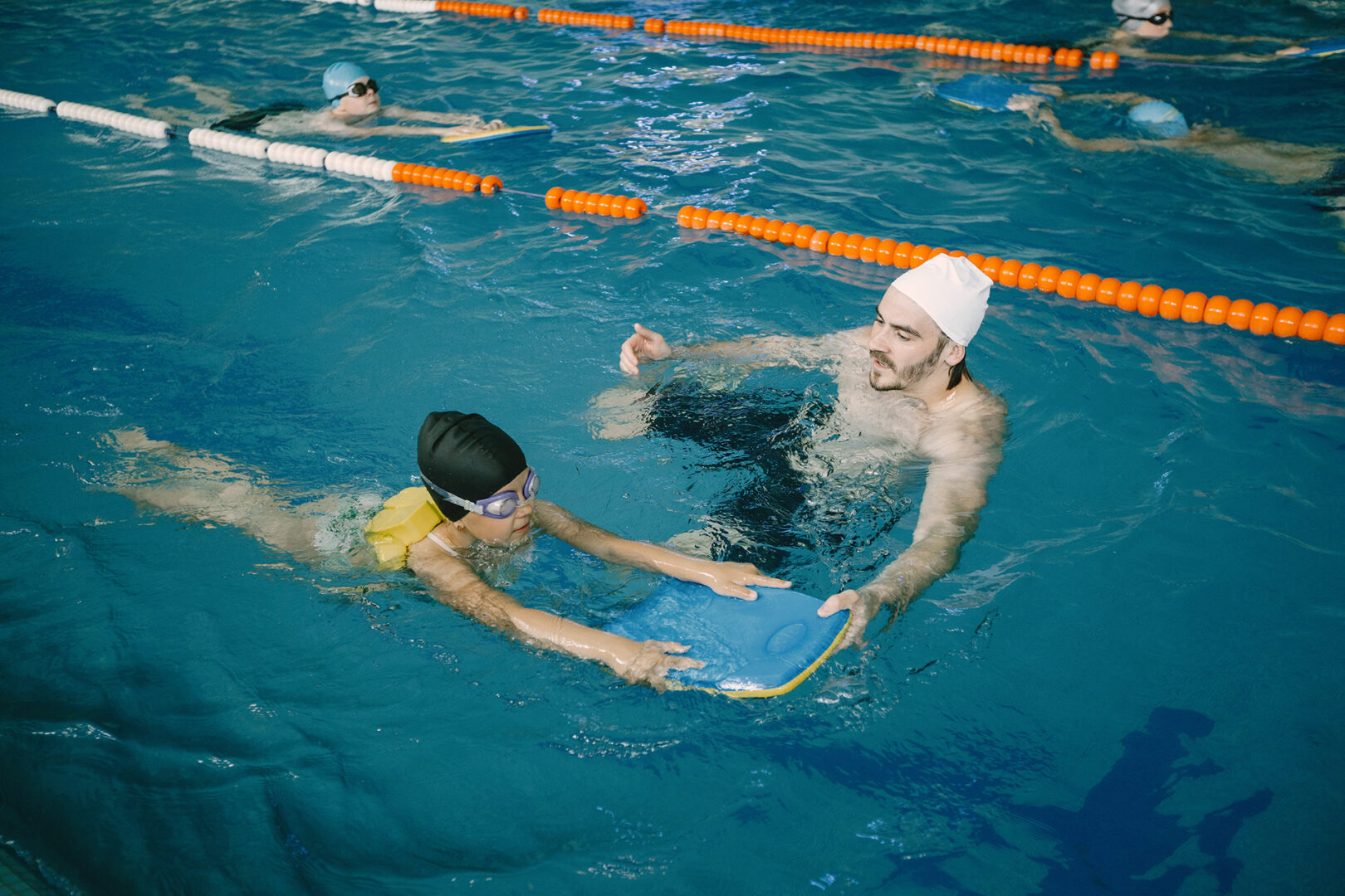 Coach teaching a child to dive in an indoor heated pool